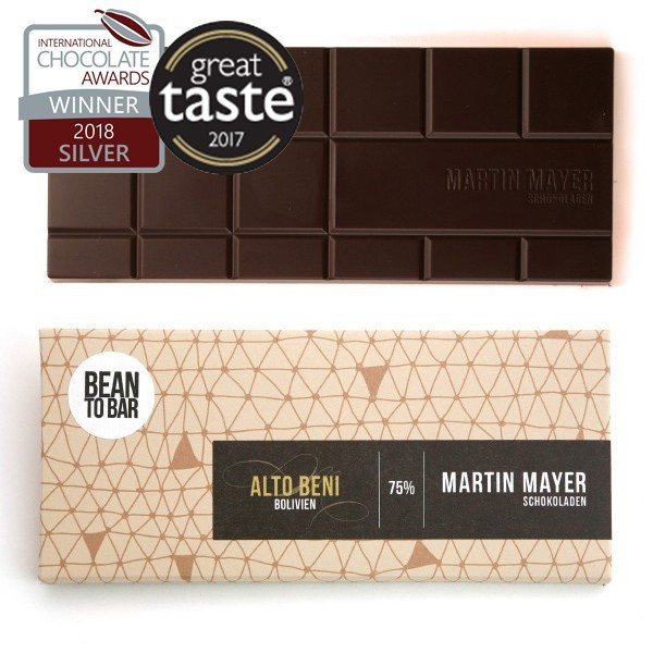 Verpackung und ausgepackte Tafel der Alto Beni-Schokolade von Martin Mayer. Die Verpackung ist beige mit dunkelbraunem Etikett und hat ein Muster aus hellbraunen illustrierten Dreiecken. 