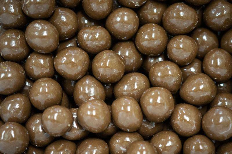 Nahaufnahme mittelbrauner dragierter Haselnüsse in Vollmilchschokolade