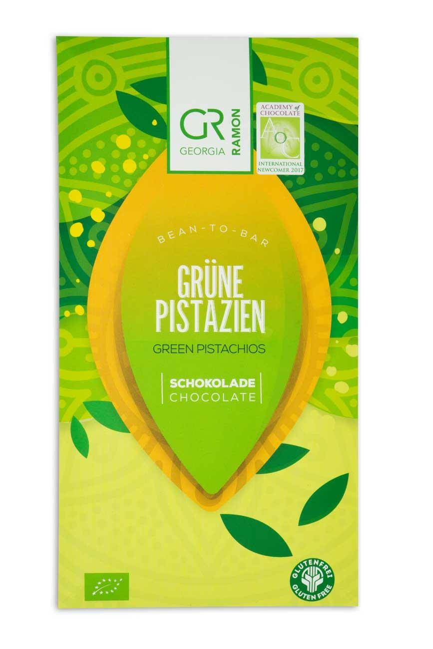 Verpackung der "GRüne Pistazien"-Schokolade von Georgia Ramon: Hellgrüne Blattmuster und pistazienförmiges Emblem mit dem Namen der Schokoade