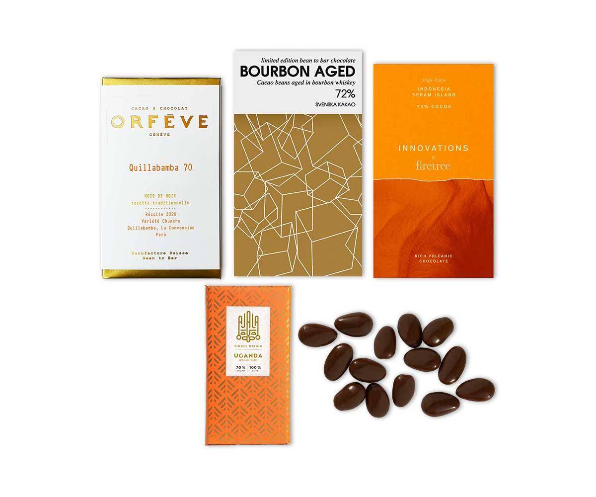 Zusammenstellung der Schokoladen für die Geschenkbox Amors Pfeil auf weißem Hintergrund - Tafeln in gold-weißer und orangefarbener Verpackung sowie einige schokolierte Mandeln