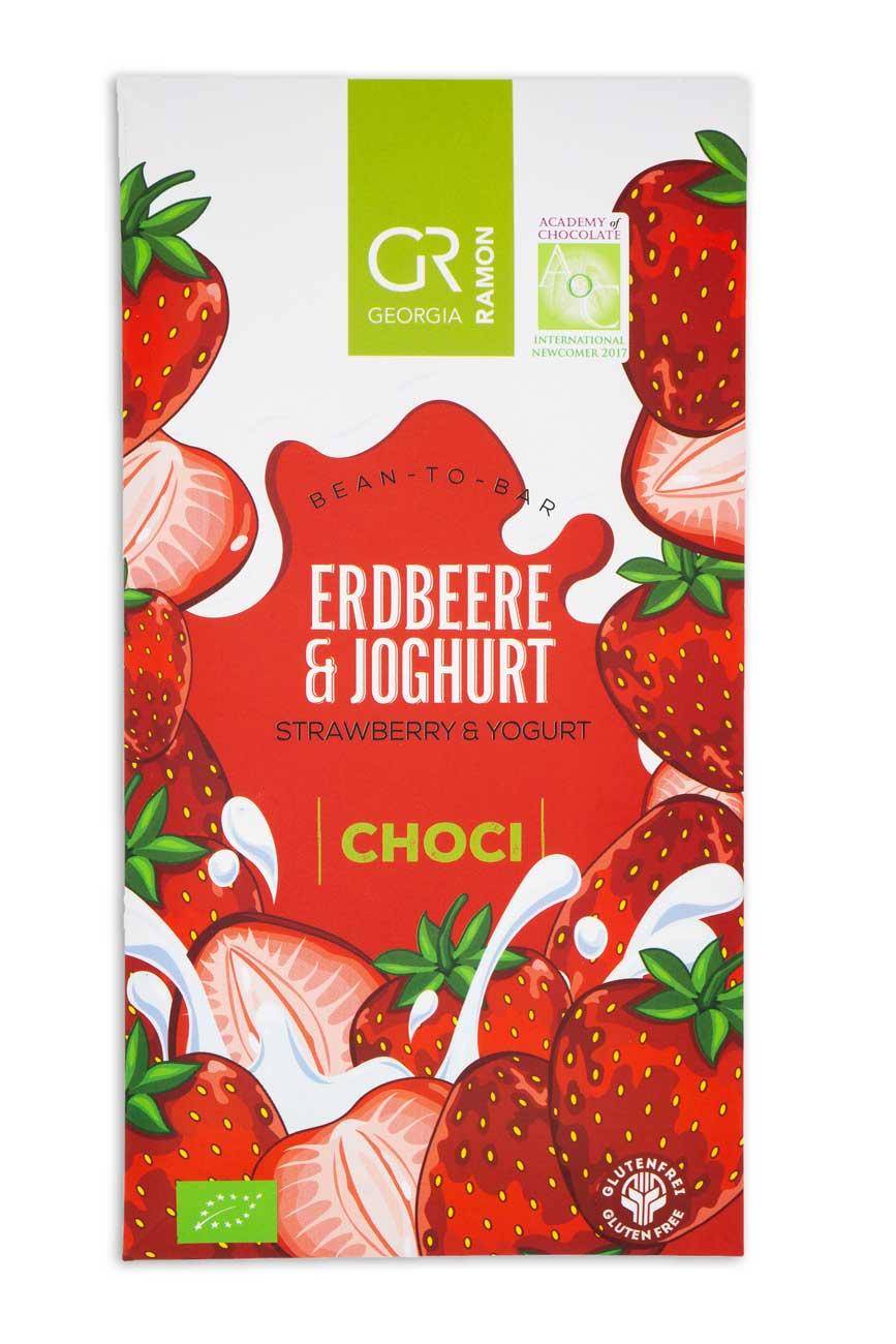 Verpackung der Erdbeer-Joghurt-Schokolade mit grafisch illustrierten Erdbeeren, rotem Hintergrund und weißem Wellenmuster und Joghurt-Spritzern