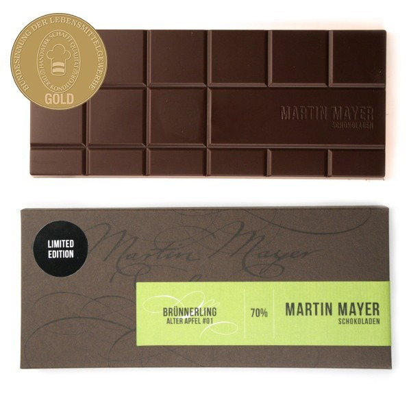 Verpackung und ausgepackte Tafel der Brünnerling-Apfel-Schokolade von Martin Mayer. Die Verpackung ist dunkelbraun mit hellgrünem Etikett.