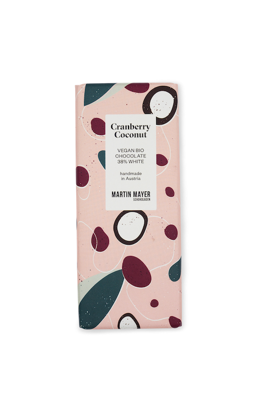 Martin Mayer Vegane Schokolade Cranberry-Kokosnuss - Verpackung aus rosa Papier mit Illustrationen von Kokosnüssen und Cranberries