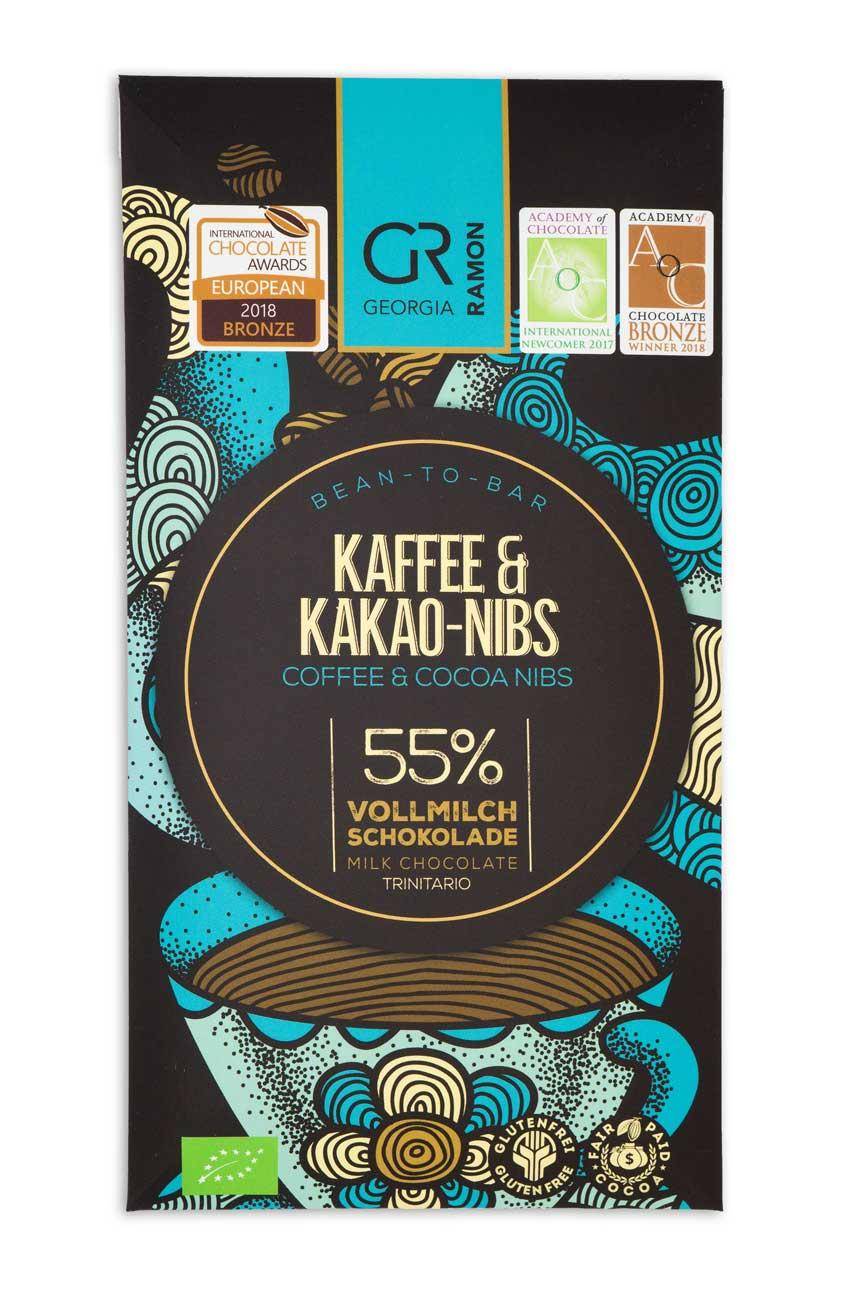 Verpackung der  "Kaffee & kakao-Nibs" Schokolade von Georgia Ramon. Schwarzer Hintergrund, im Vordergrund eine illustrierte Kaffeetasse in türkis und hellblau mit wellenförmig gemusterten Dampfschwaden