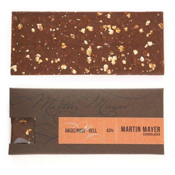 Martin Mayer Milch-Schokolade mit Haselnuss  - Verpackung aus dunkelbraunem Papier mit rotbrauner Banderole.