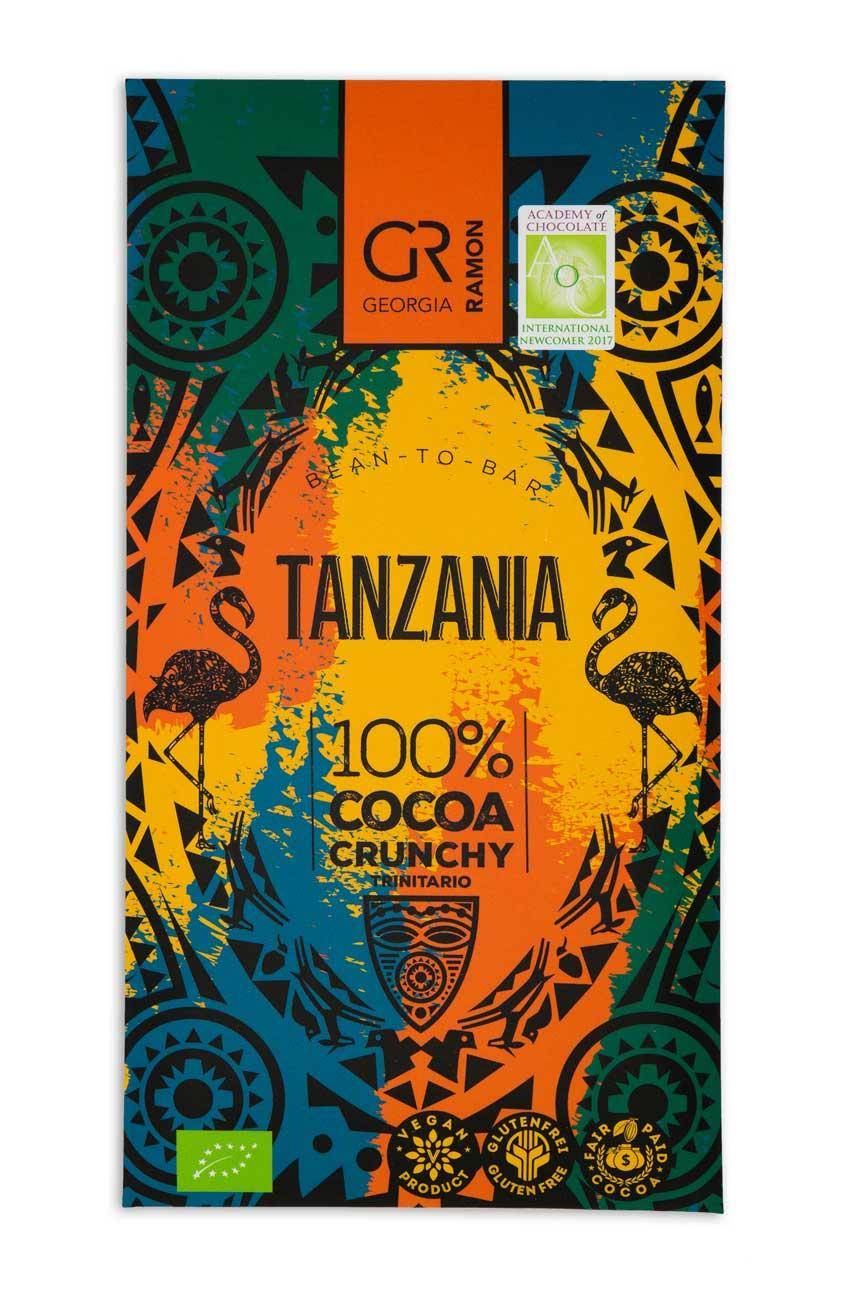 Verpackung der "Tanzania 100% Crunchy" Kakaomasse von Georgia ramon - bunter Hintergrund in gelb, rot, blau und dunkelgrün, mit afrikanischem schwarzen Muster darauf.
